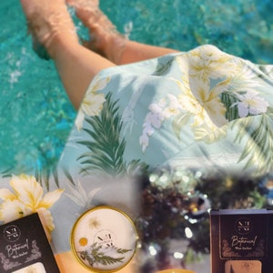 Pu&ograve; includere: Un set di due bustine di cera botanica con un design floreale. Le bustine sono confezionate in una scatola nera con testo bianco che recita "Botanical Wax Sachet".