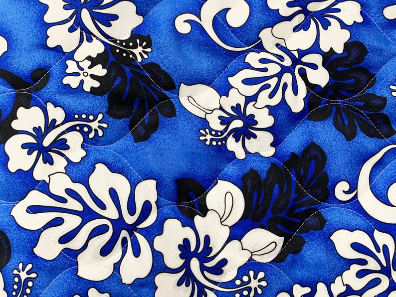May include: Blue fabric with a white and black floral pattern. The pattern features hibiscus flowers and leaves.