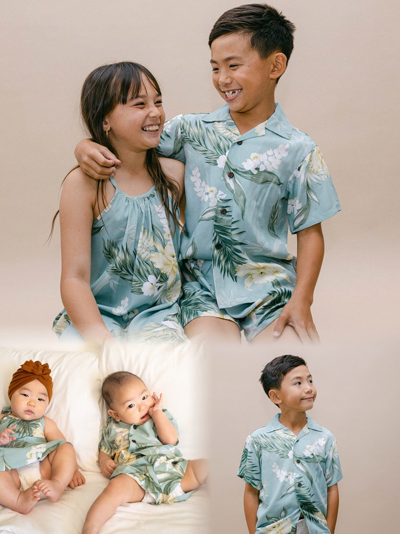 Pu&ograve; includere: Una famiglia di quattro persone vestite con abiti coordinati a stampa tropicale. I due figli maggiori sorridono e si guardano. I due figli pi&ugrave; piccoli sono seduti su un letto bianco. Gli abiti sono di colore azzurro chiaro con foglie verdi e fiori bianchi.