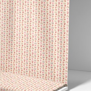 May include: A roll of fabric featuring a repeating pattern of teacups, saucers, and flowers in pink, red, and grey on a cream background. The fabric is labelled "Ninth Isle Inspiration".