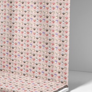 May include: A fabric roll displaying a repeating pattern of teacups filled with flowers on a pale pink backdrop. The teacups are in various colours, including red, brown, and white. The fabric is printed with a floral design.