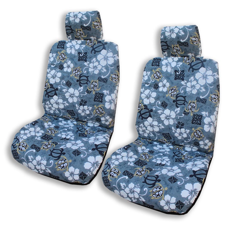 May include: Two gray car seat covers with a tropical floral pattern featuring white hibiscus flowers, black sea turtles, and gold accents.