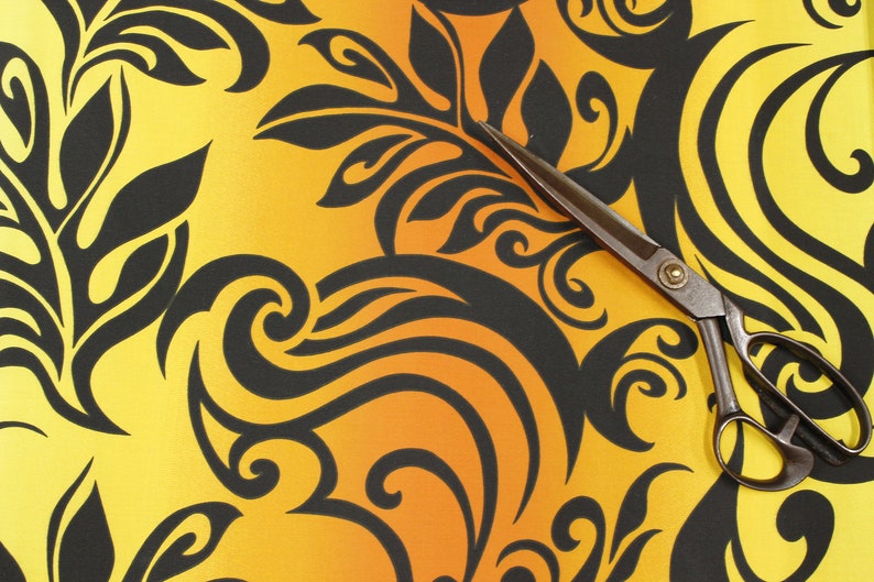 May include: A pair of black fabric scissors with a yellow and orange gradient background featuring a black floral pattern.