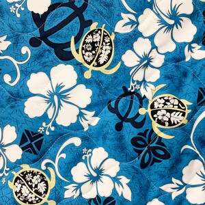 May include: Blue fabric with a repeating pattern of white hibiscus flowers, yellow and black sea turtles, and dark blue geometric shapes.
