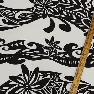 Puede incluir: Tela negra y blanca con un patr&oacute;n repetitivo de flores estilizadas y formas geom&eacute;tricas. La tela tiene un fondo blanco y el patr&oacute;n es negro. La tela se est&aacute; midiendo con una regla.