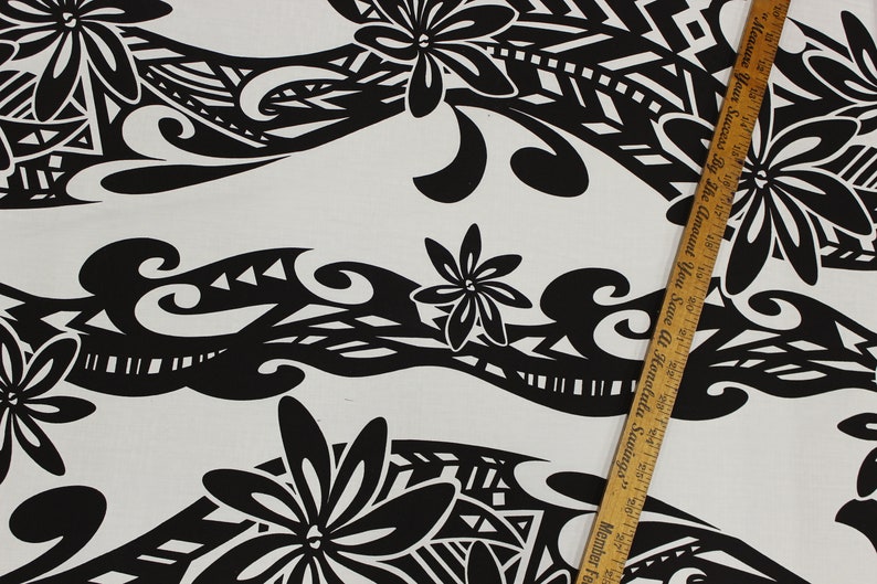 Puede incluir: Tela negra y blanca con un patr&oacute;n repetitivo de flores estilizadas y formas geom&eacute;tricas. La tela tiene un fondo blanco y el patr&oacute;n es negro. La tela se est&aacute; midiendo con una regla.