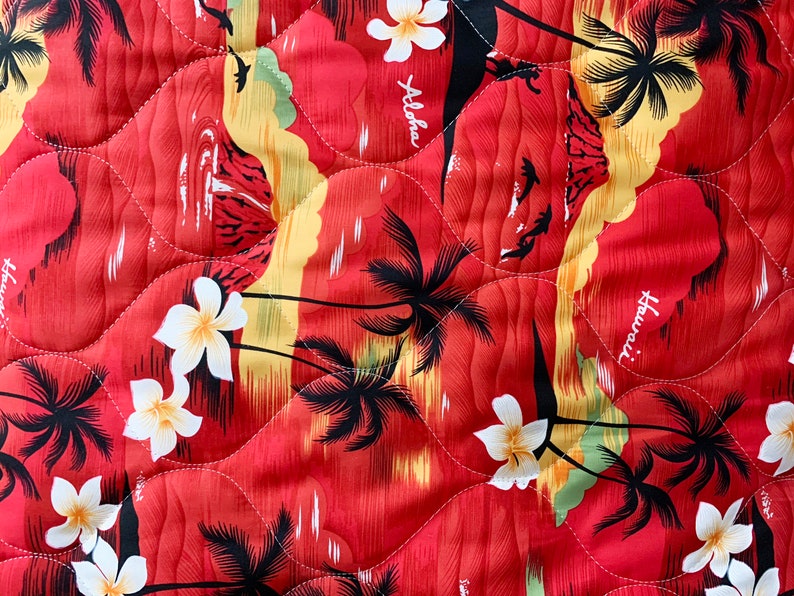 May include: Red fabric with a quilted pattern featuring a tropical print of palm trees, white flowers, and the words "Aloha" and "Hawaii".