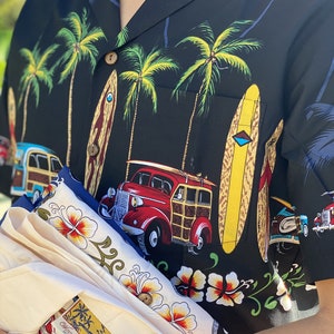 K&ouml;nnte beinhalten: Ein schwarz-wei&szlig;es Hawaii-Hemd mit Palmen, Surfbrettern und einem alten Holz-Kombi. Das Hemd ist gefaltet und wird von einer Person gehalten. Das Hemd hat ein Etikett mit der Aufschrift "Charlie Trotter, Made in Hawaii".