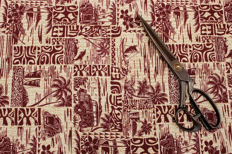 Puede incluir: Un par de tijeras vintage con mango de madera marr&oacute;n y hoja de metal plateado, sobre una tela con estampado hawaiano rojo y blanco.