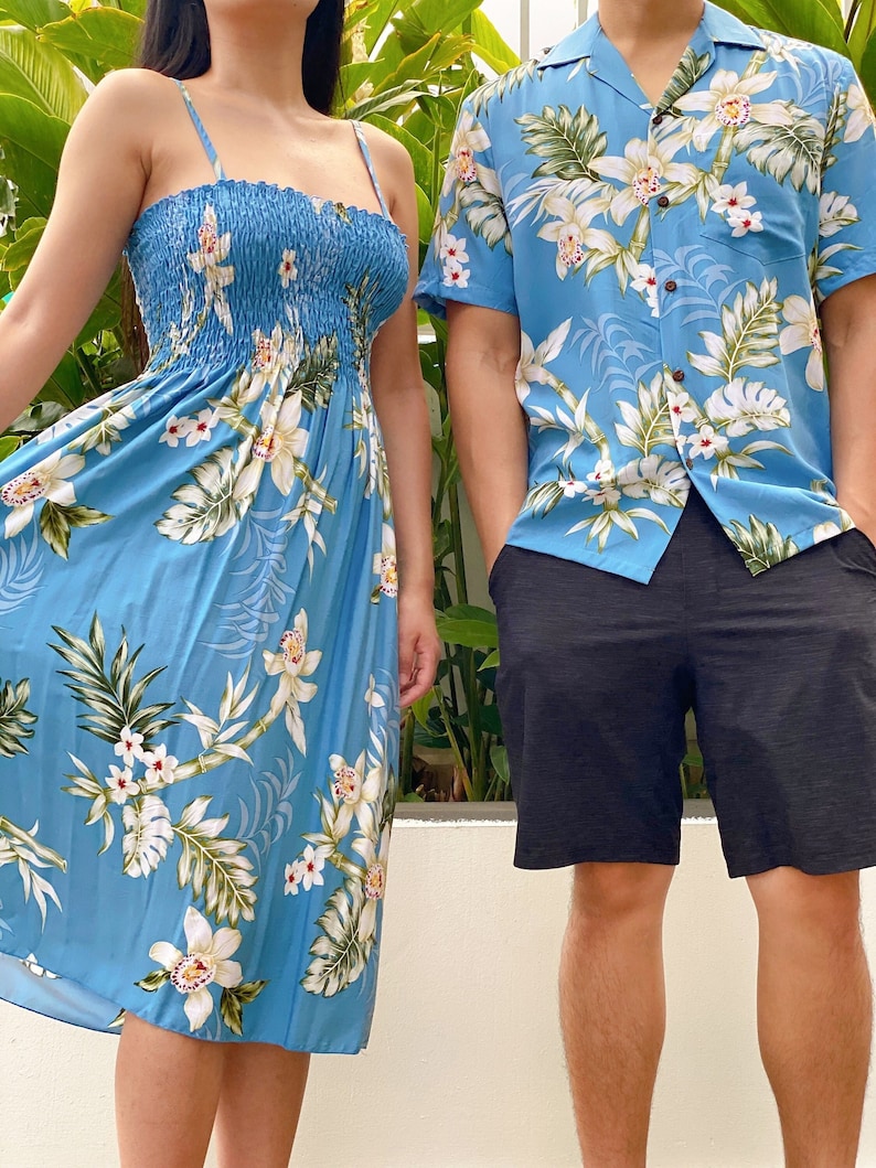 K&ouml;nnte beinhalten: Ein Paar tr&auml;gt passende Kleidung mit blauem Blumendruck. Die Frau tr&auml;gt ein &auml;rmelloses Kleid mit wei&szlig;em Blumenmuster. Der Mann tr&auml;gt ein kurz&auml;rmeliges Hemd mit wei&szlig;em Blumenmuster und schwarze Shorts.