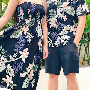K&ouml;nnte beinhalten: Ein schwarzes und wei&szlig;es Kleid mit Blumenmuster und ein passendes Hemd. Das Kleid hat ein tr&auml;gerloses Design mit einem gerafften Oberteil und einem flie&szlig;enden Rock. Das Hemd hat kurze &Auml;rmel und einen Kragen.