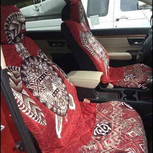 May include: Two red car seat covers with a brown and white patterned design featuring a turtle. The pattern is a traditional Polynesian design.