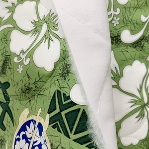 May include: Close-up of a green and white fabric with a floral pattern. The fabric is quilted and has a white backing.