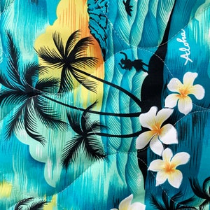May include: A blue and yellow fabric with a tropical print featuring palm trees, waves, and flowers. The fabric has the word "Aloha" printed on it.