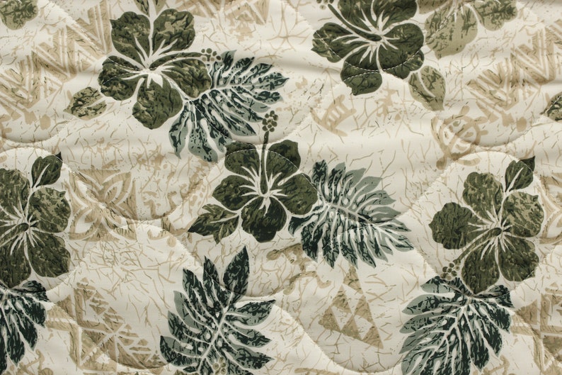 May include: A white fabric with a green and brown floral pattern. The pattern features hibiscus flowers and leaves.