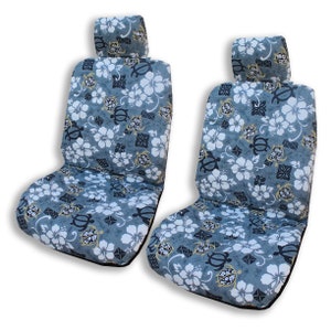 May include: Two gray car seat covers with a tropical floral pattern featuring white hibiscus flowers, black sea turtles, and gold accents.