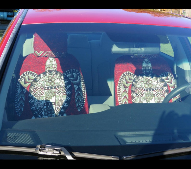 May include: Two red car seat covers with a green and white turtle design. The covers are made of a soft, comfortable fabric and feature a Hawaiian-inspired pattern.