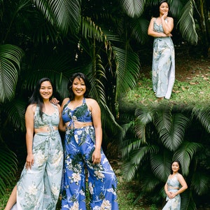 Pu&ograve; includere: Due persone che indossano pantaloni e top abbinati con stampa floreale blu e bianca. I pantaloni hanno una gamba larga e i top hanno un nodo sul davanti. Le persone sono in piedi davanti a uno sfondo tropicale verde lussureggiante.