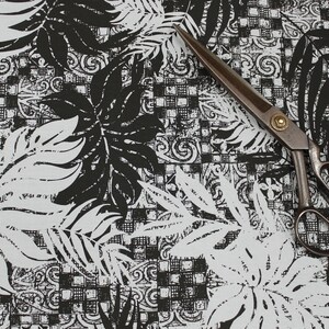 Puede incluir: Tela negra y blanca con un patr&oacute;n repetitivo de hojas y formas geom&eacute;tricas. Un par de tijeras de metal negro est&aacute; sobre la tela.