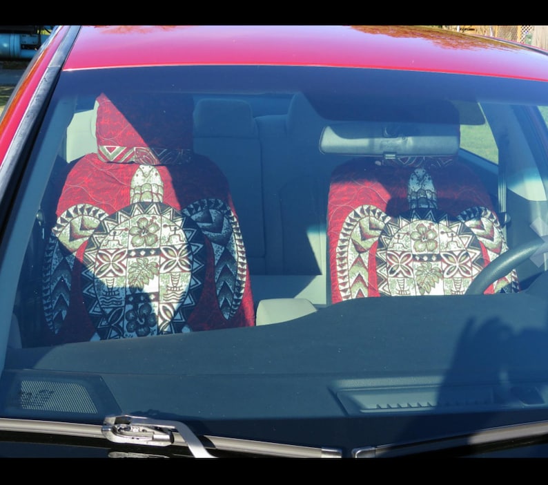 May include: Two red car seat covers with a green and white turtle design. The covers are made of a soft, comfortable fabric and feature a Hawaiian-inspired pattern.