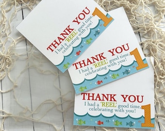 May include: Three white thank you cards with a fishing theme. Each card has the text "THANK YOU" in red, and "I had a 'REEL' good time, celebrating with you!" The cards have a blue wave design with fish and the number 1.