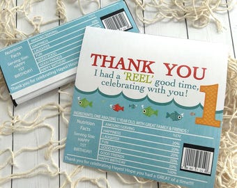 May include: Two light blue and white birthday party favor cards with a fish theme. One card says "Thank You" and the other has a nutrition facts label. The cards have a fish and wave design.