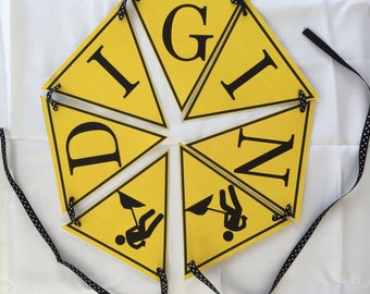 May include: Yellow triangular pennant banner with black letters spelling "DIG IN" and two black stick figures holding shovels.