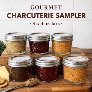 May include: A gourmet charcuterie sampler featuring six 4 oz jars of various spreads. The jars are filled with different colored contents and are arranged on a wooden board. The jars have silver lids and labels. The text "GOURMET CHARCUTERIE SAMPLER" is at the top.
