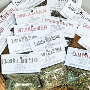 May include: A collection of small, clear plastic bags filled with various dried herbs and spices. Each bag has a white label with the name of the blend printed in black. The blends include: Lemon Dill Herb Blend, Ranch Herb Blend, Garden Herb Blend, Italian Cheese Herb, Cheddar Cheese & Bacon, Mediterranean Herb, Horseradish Herb Blend, Salsa Herb Blend, Herbal Butter Blend, and Chili Cheese.