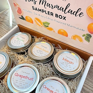May include: A sampler box of six 4-ounce jars of citrus marmalade. The jars are labeled with the flavors: Key Lime, Lemon Delight, Grapefruit, Mango, and Orange Citrus. The box is filled with shredded paper.