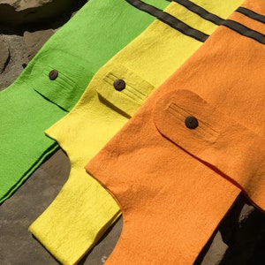 May include: Three felt fabric bags in green, yellow, and orange with black stripes and brown buttons. The bags are folded and stacked on top of each other.