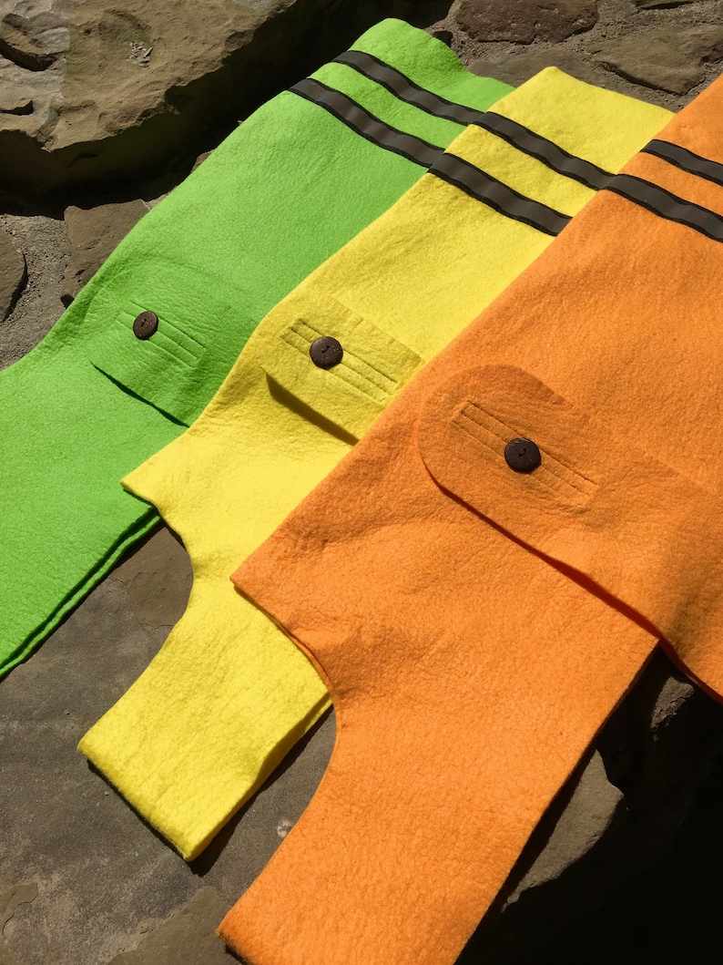 May include: Three felt fabric bags in green, yellow, and orange with black stripes and brown buttons. The bags are folded and stacked on top of each other.