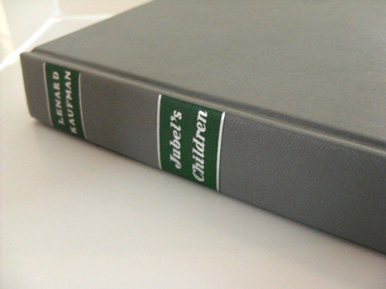 May include: A hardback book with a grey cover. The spine features green and white labels with the title "Jubel's Children" and the author's name, Lenard Kaufman, printed in white.