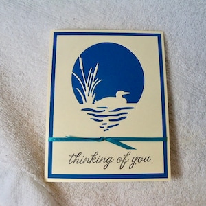 Carte de voeux pour toutes les occasions, choix de voeux, vierge à l'intérieur. Modèle découpé élégant représentant un huard nageant, fait main avec une décoration en ruban.