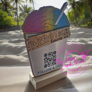 May include: A wooden sign shaped like a shaved ice cup with a rainbow-colored shaved ice design. The sign says "Parrot Ice Shaved Ice" and has a QR code with the text "Follow & Tag The House That Junk Built".