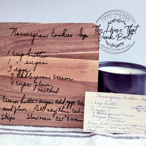 Puede incluir: Una tabla de cortar de madera con una receta manuscrita para galletas noruegas. La receta incluye 1 taza de mantequilla, 1 taza de azúcar, 3 huevos, 3 cucharadas de crema y 4 tazas de harina. La tabla está grabada con el texto "The House That Junk Built".