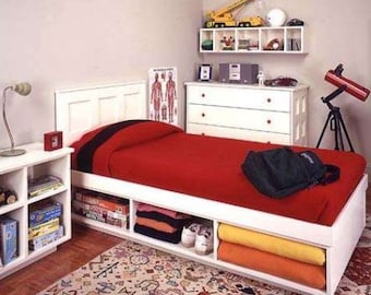 Puede incluir: Estructura de cama blanca de tamaño individual con un edredón rojo y un cubrecama con estampado en blanco y negro. La cama tiene estantes de almacenamiento integrados debajo. La cama está en un dormitorio con una cómoda blanca y una estantería blanca con juguetes y un telescopio.