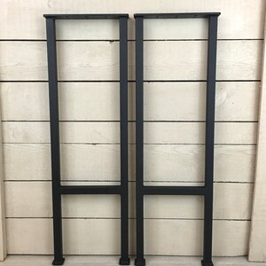 Puede incluir: Dos patas de mesa de metal negro con un dise&ntilde;o simple en forma de H. Las patas est&aacute;n hechas de tubo cuadrado y tienen un acabado negro mate.