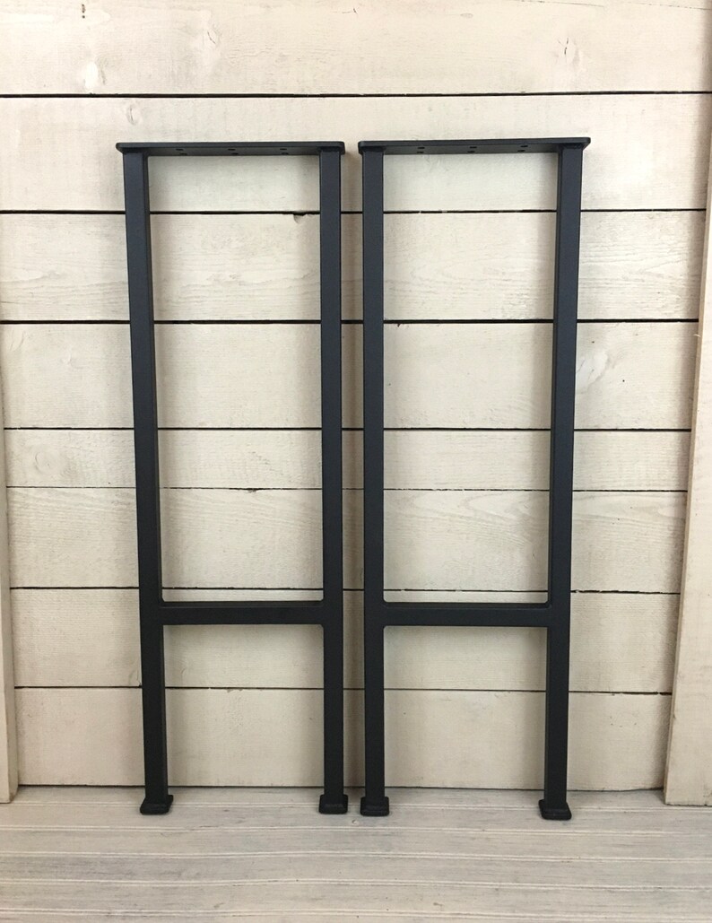 Puede incluir: Dos patas de mesa de metal negro con un dise&ntilde;o simple en forma de H. Las patas est&aacute;n hechas de tubo cuadrado y tienen un acabado negro mate.
