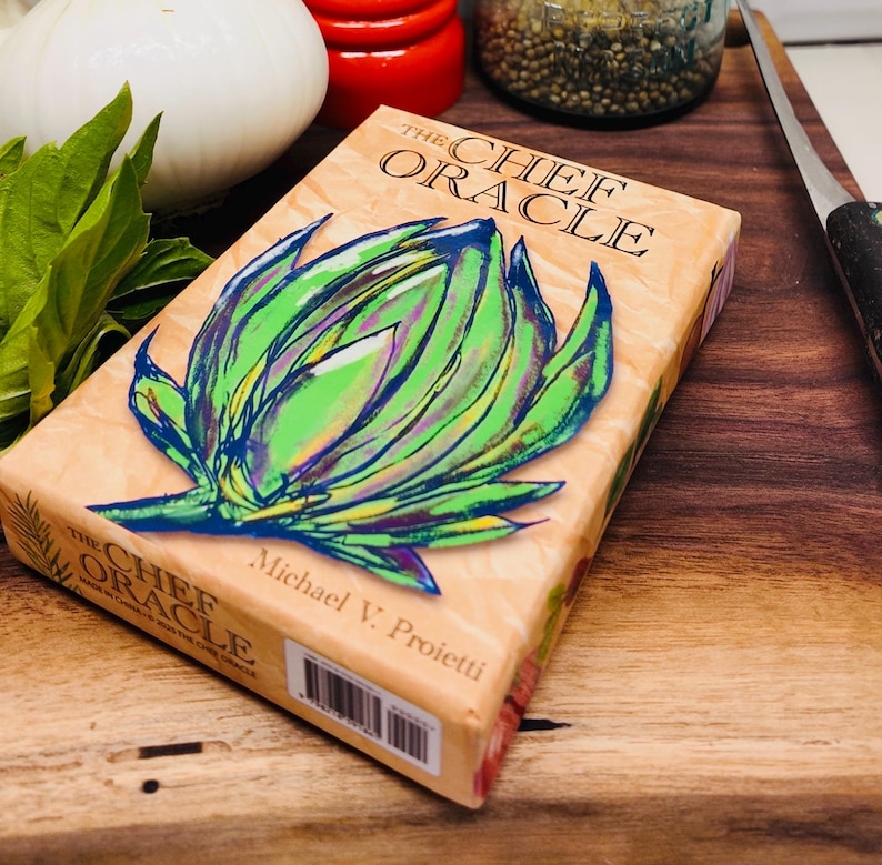 May include: The Chef Oracle card deck box with a green and purple artichoke illustration on the front. The text on the box reads 'The Chef Oracle' and 'Michael V. Proietti'.