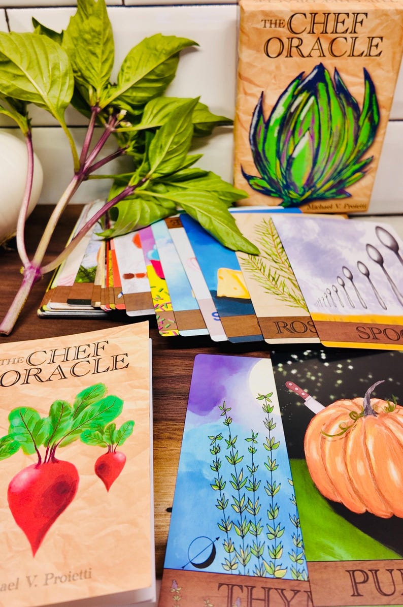 May include: A collection of "The Chef Oracle" cards and a book, featuring colorful illustrations of vegetables, herbs, and kitchen tools. Fresh basil with purple stems and green leaves is in the foreground. The cards have text like "ROS" and "SPO".