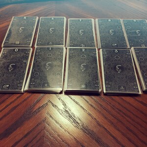 May include: A set of ten black cards with white numbers and designs. The cards are numbered 0 through 9.