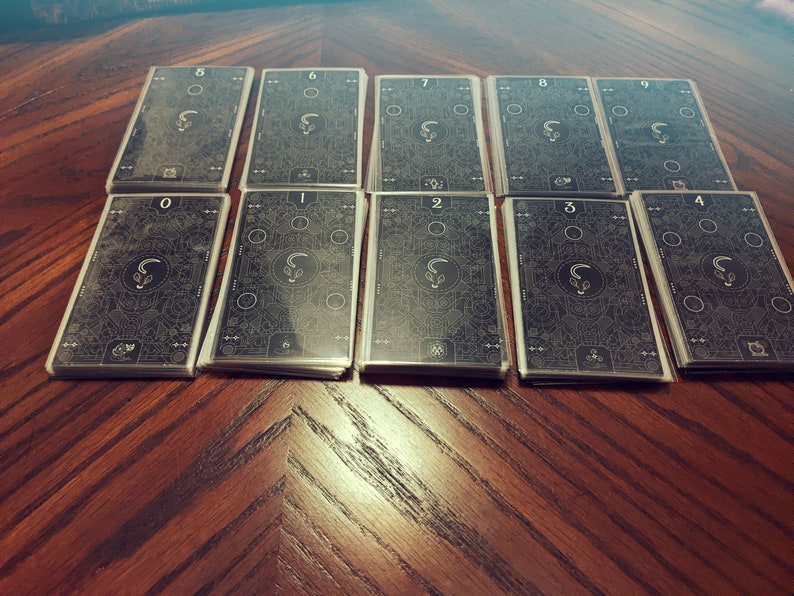 May include: A set of ten black cards with white numbers and designs. The cards are numbered 0 through 9.