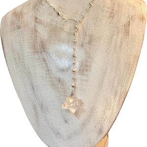 Pode incluir: Uma caneca de cerâmica branca com uma alça preta e o texto "But First, Coffee" em negrito preto. A caneca está sobre um fundo desfocado, sugerindo um ambiente acolhedor.