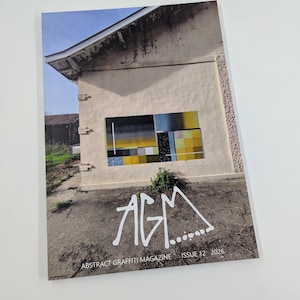 Puede incluir: Una portada de revista con una fotografía de un edificio y una obra de arte abstracta. El título de la revista "AGM" está en letras blancas estilizadas. También se ve el texto "ABSTRACT GRAFFITI MAGAZINE ISSUE 12 2026".