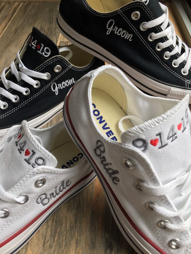 K&ouml;nnte beinhalten: Ein Paar wei&szlig;e und schwarze Canvas-Schuhe mit den Worten "Bride" und "Groom", die darauf gestickt sind. Die Schuhe haben auch das Datum "9.14" und ein Herz, das darauf gestickt ist.