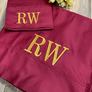 May include: Two burgundy pillowcases with gold embroidered initials "RW" on each.