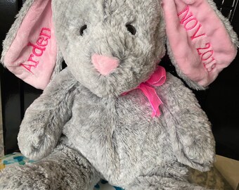 May include: A gray plush bunny with pink ears. The ears are embroidered with the name "Arden" and the date "Nov 2018".