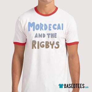 Op de afbeelding: Wit ringer t-shirt met rode randen op de kraag en mouwen. De tekst "Mordecai and the Rigbys" staat in blauwe en bruine letters op de shirt. Het Based Tees logo is zichtbaar.