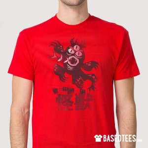 Könnte beinhalten: Rotes T-Shirt mit einem schwarzen und roten Monster-Motiv und dem japanischen Text "怪獣" (Kaiju) auf der Vorderseite.
